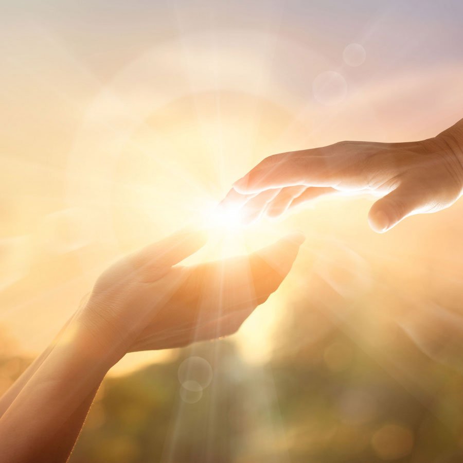 Two hands reaching towards each other in warm sunlight